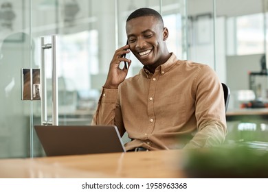 Young African businessman talking on his cellphone and using a laptop
