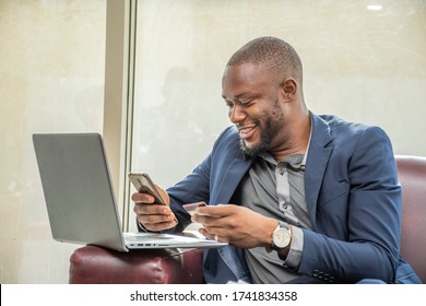 A Young African Businessman Using His Credit Card And Mobile Phone, Online Banking Concept