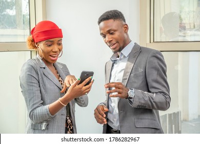 young african businesswoman and businessman having a meeting standing, viewing something on a mobile phone