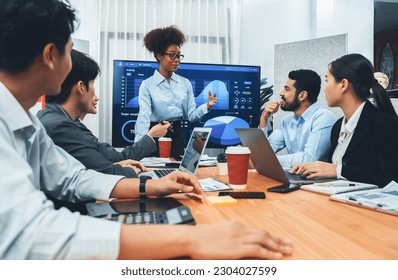 Young african businesswoman presenting data analysis dashboard on TV screen in modern meeting. Business presentation with group of business people in conference room. Concord - Powered by Shutterstock