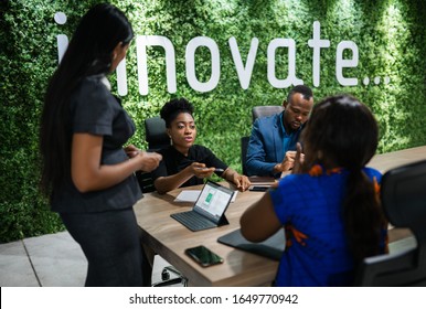 Young African businesswoman talking with a group of work colleagues during a meeting together around a table in an office boardroom