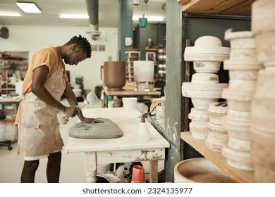 Young African ceramist hitting a piece of clay with a mallet - Powered by Shutterstock