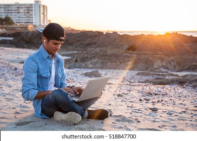 Young African Coloured Man Working On Laptop At The Beach, Cape Town, South Africa