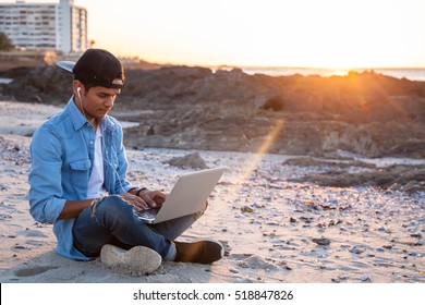 Young African Coloured Man Working On Laptop At The Beach, Cape Town, South Africa