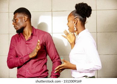 young African couple arguing, woman wants to talk to the man while he refuses to listen. she looks sad and angry