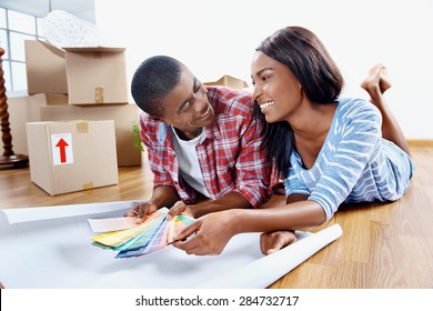 young african couple having fun deciding on paint colour swatch for new home apartment - Powered by Shutterstock