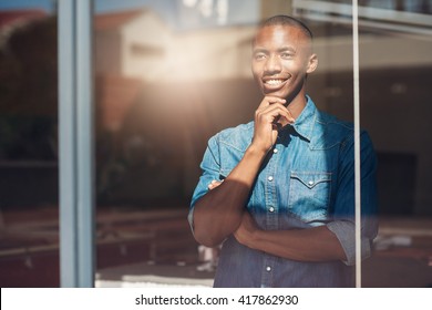 Young African designer looking through window thinking about the future - Powered by Shutterstock