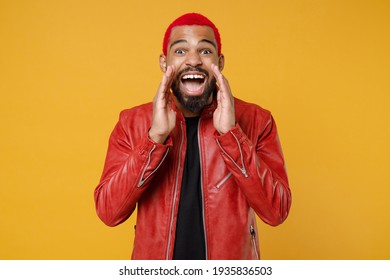 Young African Excited Expressive Man 20s With Funky Trendy Pink Hairdo Wearing Red Leather Jacket Scream News With Hands Near Mouth Isolated On Bright Yellow Orange Color Background Studio Portrait