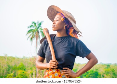 Young African Farmer Holding A Hoe On Her Shoulder Resting