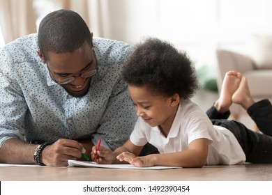 Young african father drawing with little preschool son family lying on warm floor at modern home, older brother helps to younger learn to paint, contemporary house, leisure activities with kid concept - Powered by Shutterstock