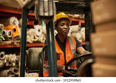 Young African female forklift driver moving packages around the floor of a textile warehouse - Powered by Shutterstock