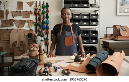 Young African female leather worker standing by a work table