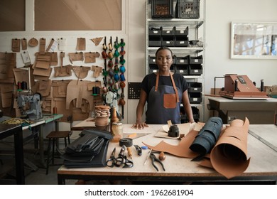 Young African female leather worker standing by a workbench
