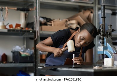 Young African female leather worker using a mallet and punch
