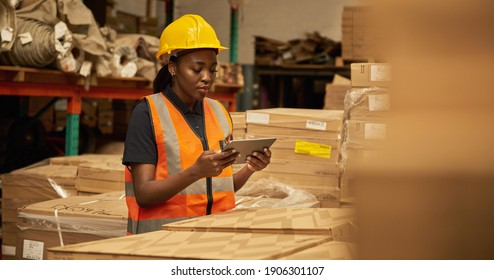 Young African female warehouse worker working on a digital table during an iventory check