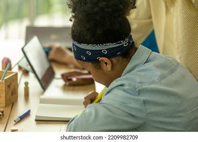 A Young African Girl Is Doing Study With Support From Her Teacher. A Kid Concentrates On Her Literature Review In A Class