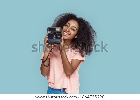 Young african girl standing isolated on gray background holding instant camera smiling happy
