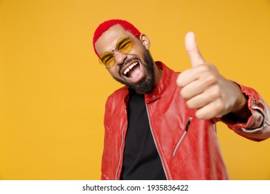 Young african happy man 20s with funky trendy pink hairdo wearing stylish red leather jacket sunglasses show close up thumb up like gesture isolated on yellow orange color background studio portrait - Shutterstock ID 1935836422
