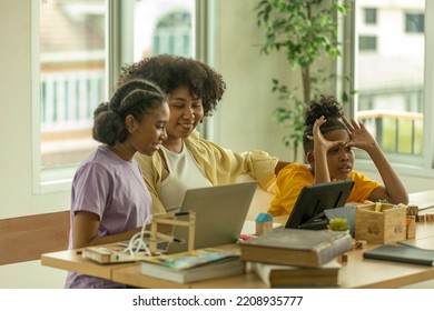 Young African Kids Get Support From A Teacher To Use Tablet For An Online Class. A Class Of African Pupil Taking Online Learning Program Through Computer Notebook.