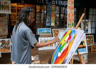 Young african male artist with dreadlock painting a colorful animal on canvas standing in studio - Powered by Shutterstock