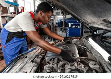 Young African male mechanic repairs car in garage close up - Powered by Shutterstock