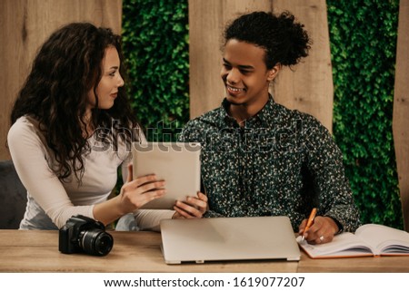Young african man and american woman working in modern coworkong space with laptop and tablet