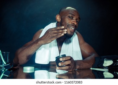 The young african man in bedroom sitting in front of the mirror after scratching his beard at home. Human emotions concept. after shave cream concepts - Powered by Shutterstock