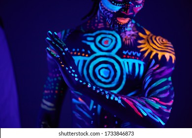 young african man blur with ultraviolet body art, fluorescent prints glows on neon light, isolated in studio. mystery, luminescence, fluorescence, ethnic body art