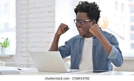 Un jeune Africain célèbre son succès sur un ordinateur portable