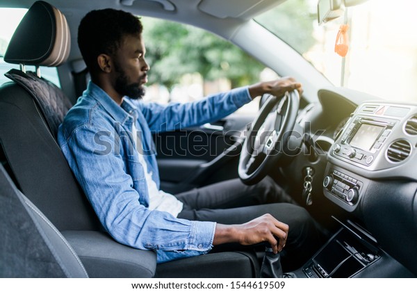 Young african\
man change gear while driving\
car