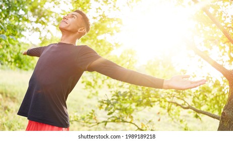 Young african man doing breathing exercise for relaxation in nature in summer