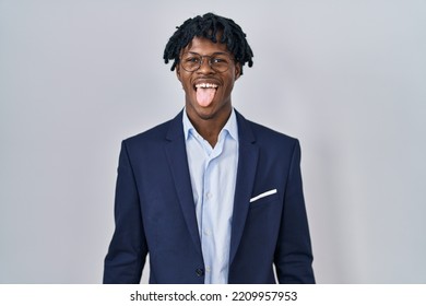 Young african man with dreadlocks wearing business jacket over white background sticking tongue out happy with funny expression. emotion concept. 