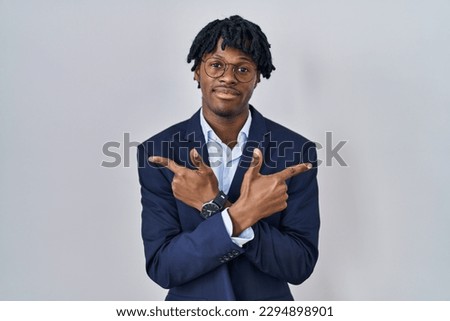 Young african man with dreadlocks wearing business jacket over white background pointing to both sides with fingers, different direction disagree 