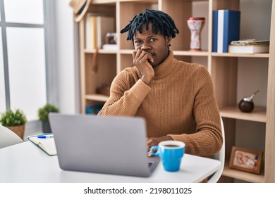 Young African Man With Dreadlocks Working Using Computer Laptop Looking Stressed And Nervous With Hands On Mouth Biting Nails. Anxiety Problem. 