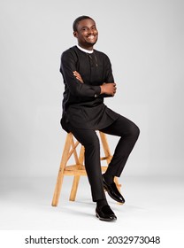young african man dressed in stylish native attire smiling, sitting on a stool - Shutterstock ID 2032973048