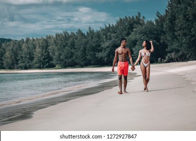 Young African man and his smiling girlfriend enjoying a late afternoon together at the beach. Phuket. Thailand