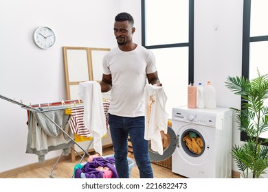 Young African Man Holding Clean White T Shirt And T Shirt With Dirty Stain Skeptic And Nervous, Frowning Upset Because Of Problem. Negative Person. 