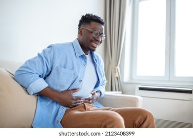 Young African Man Holding His Stomach In Pain, Man With Reflux Disease Holding His Belly With Painful Expression