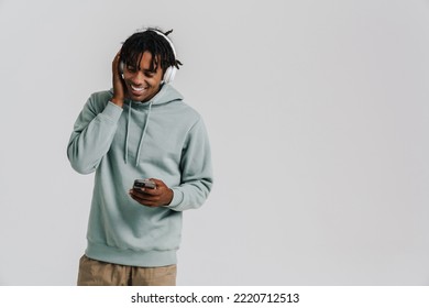 Young african man listening music with headphones using mobile phone isolated over white background
