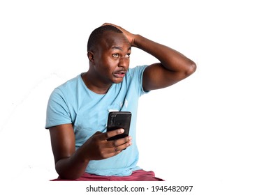 A Young African Man Looking At His Phone In Shock And Regret