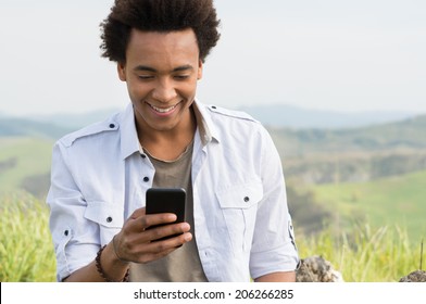 Young African Man Looking At Mobile Phone