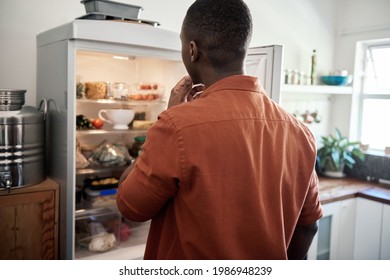 Young African man looking for something in his fridge