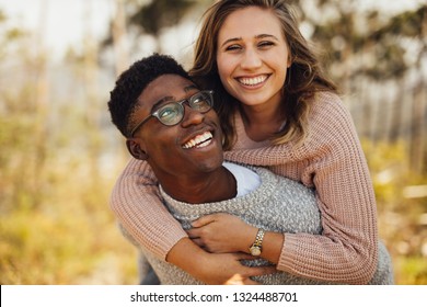 Young African Man Piggybacking His Girlfriend. Interracial Couple Having Fun Outdoors.