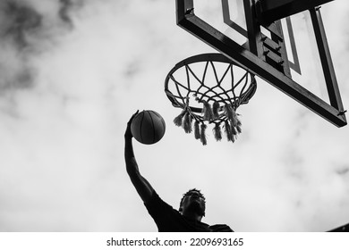 Young African Man Playing Basketball Outdoor - Focus On Rim - Black And White Editing