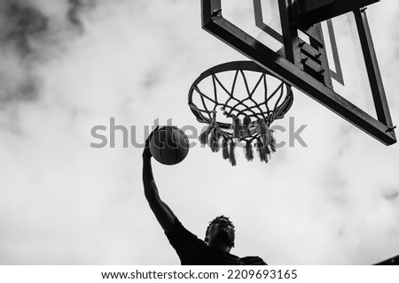 Young african man playing basketball outdoor - Focus on rim - Black and white editing