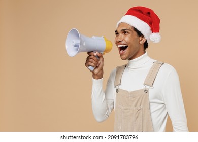 Young African Man In Santa Claus Red Christmas Hat Hold Scream In Megaphone Announces Discounts Sale Hurry Up Isolated On Plain Pastel Beige Background Studio. Happy New Year 2022 Celebration Concept