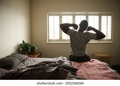 Young African man stretching on his bed in the morning - Shutterstock ID 2052568184