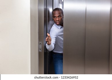 Young African Man Trying To Stop Elevator Door With His Hand