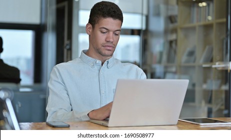 Young African Man using Laptop in Modern Office - Shutterstock ID 1690508977