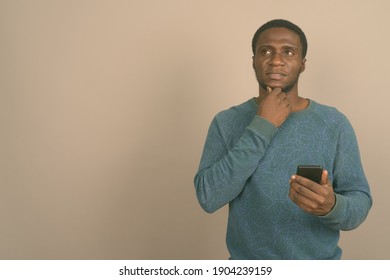 Young African man using mobile phone against gray background